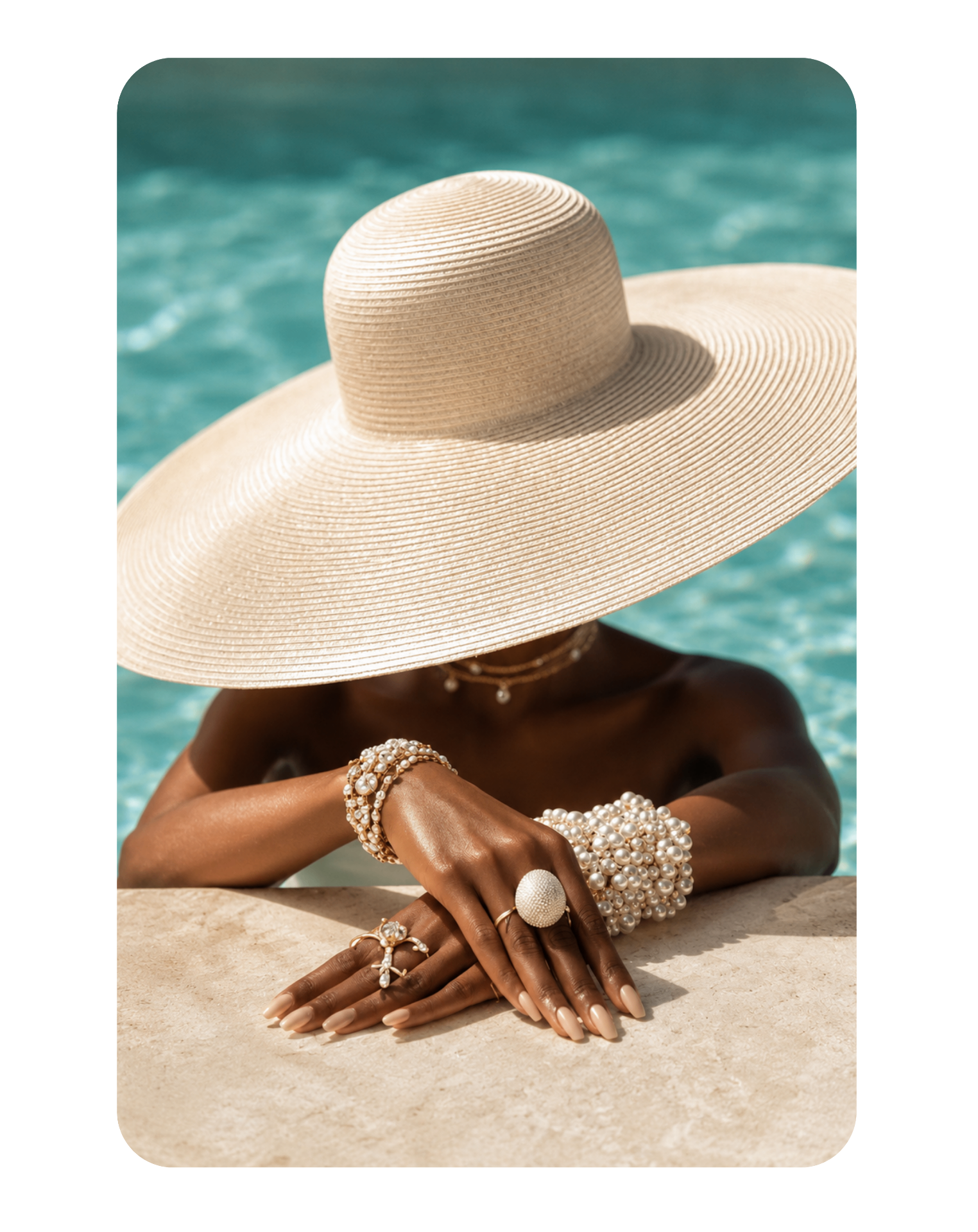 Sombrero de ala ancha y joyería de perlas junto a la piscina